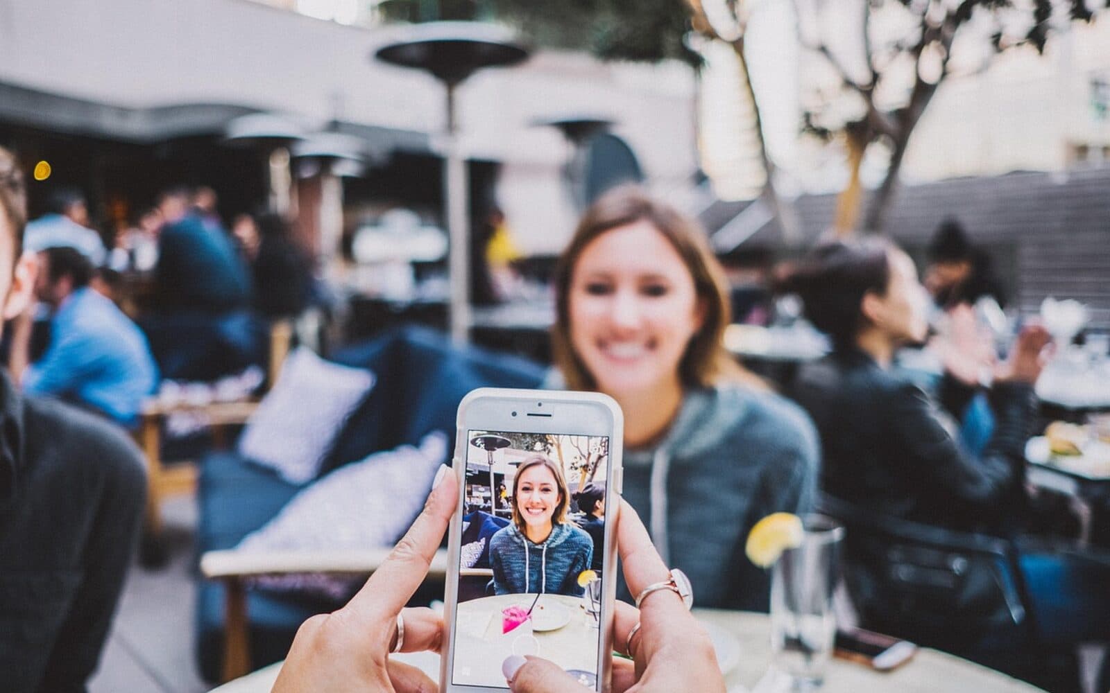 Concept image of a student holding up a smartphone showing the Student Life app at an outdoor café, ready to redeem an exclusive student discount.